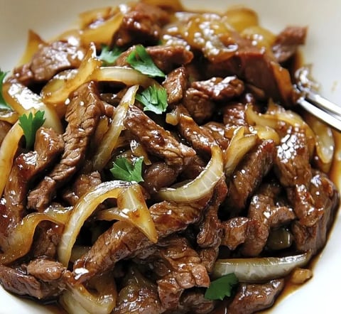 Une assiette de beef chinois avec des onions et des herbes.